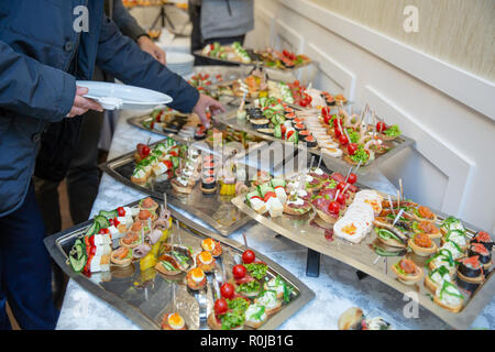 Catering tabella set service vari snack su un tavolo a banchetto. Set di spuntini freddi, crostino, bevande, primo piano. Vista laterale. Tabella per banchetti Foto Stock