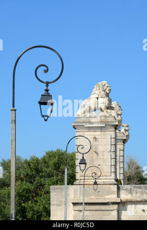 Strada contemporanea luci o lampade e leoni scolpiti nella pietra in cima a colonne o ex sospensione ponte attraverso il Fiume Rodano ad Arles Provence Francia Foto Stock