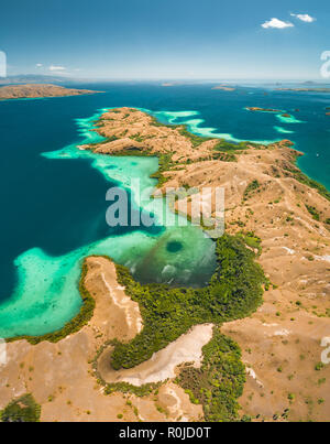 Le baie, terre di savana, oceano. Komodo. Vista aerea. Panorama spettacolare al di sopra delle splendide baie e territorio di savana del Parco Nazionale di Komodo. Indonesia. Patrimonio dell'umanità. Panoramica drone shot. Foto Stock