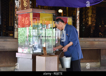 Lavoratori anziani la rimozione di candele bruciato nel tempio di Kyoto Foto Stock