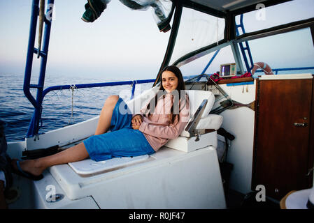 Ritratto di una giovane ragazza distesa in una barca durante una escursione in mare all'alba Foto Stock
