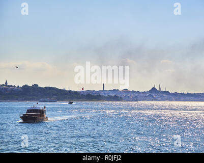 Una barca che attraversa il Bosforo, con quartiere Eminonu in background. Istanbul, Turchia. Foto Stock