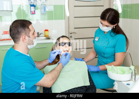 Persone, medicina, stomatologia e health care concetto - maschio dentista e assistente dentale con luce e specchio di trattamento paziente donna denti a Foto Stock