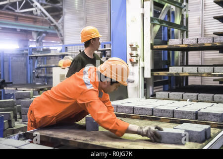Tyumen, Russia - Agosto 13, 2013: creazione di blocco dipartimento al materiale di costruzione fabbrica ZHBI-5. Lavoratori presso la macchina sui blocchi di pietra di essiccazione Foto Stock