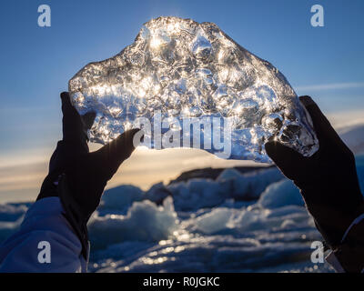 Grandi cristalli di ghiaccio in mani nel centro turistico di guanti, cielo di sera, occhi visualizza Foto Stock