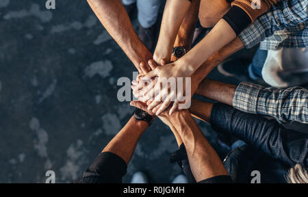 Vista dall'alto di professionisti della creatività di mettere le loro mani insieme come un simbolo di un lavoro di squadra, la cooperazione e l'unità. Pila di mani di uomo e donna. Foto Stock