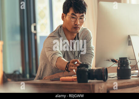 Fotografo di accendere la telecamera per trasferire le foto sul suo computer dopo lo scatto. Fotografo facendo post produzione sulle foto dopo photosho Foto Stock