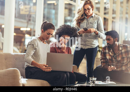 Colleghi seduti in ufficio che condividono idee. donna d'affari che presenta le sue idee su un notebook al suo team. Foto Stock