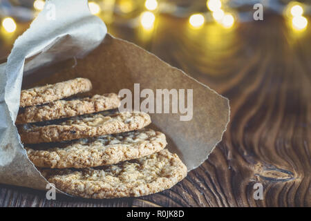 In casa i fiocchi d'avena i cookie in una pasticceria sacchetto di carta di cottura su una tavola di legno tavolo rustico vacanza invernale ancora vita Natale o Capodanno card Foto Stock