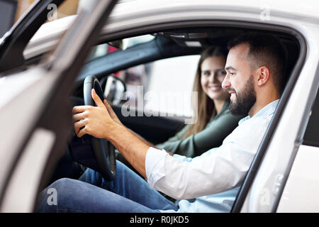 Adulto Giovane scegliendo nuova auto in showroom Foto Stock