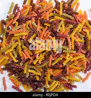 Paste alimentari non cotte a spirale colorata fusilli fatti da farina di frumento Frumento su uno sfondo bianco, vista dall'alto Foto Stock