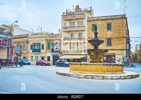 VICTORIA, Malta - 15 giugno 2018: la vecchia fontana di pietra decora San Francesco square, piena di caffetterie e negozi, il 15 giugno a Victoria. Foto Stock