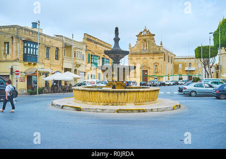 VICTORIA, Malta - 15 giugno 2018: Ensemble storico di San Francesco piazza con vecchie case, fontana e San Frangisk (San Francesco) Chiesa sullo sfondo Foto Stock