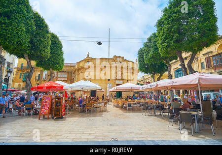 VICTORIA, Malta - 15 giugno 2018: Independence Square è il posto ideale dove rilassarsi nel ristorante all'aperto all'ombra di umbellas e alberi tagliati con un vi Foto Stock