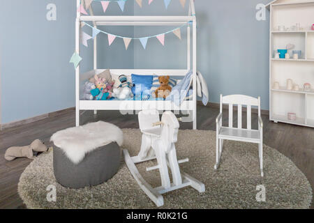 Cavallo di legno in un kids boy room interior.Mobilio elegante in un monocromatico e spaziosa stanza dei ragazzi.moderno ed elegante camera bambino interiore con una piccola e decorata del bambino.letto tradizionale cavallo a dondolo giocattolo Foto Stock