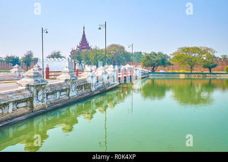 Il vecchio ponte che attraversa il fossato conduce alla porta della cittadella medievale di Palazzo Reale, Mandalay Myanmar. Foto Stock