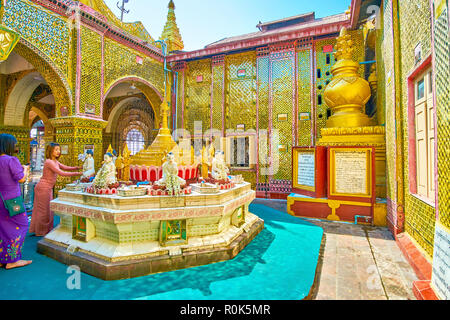 MANDALAY, MYANMAR - 23 febbraio 2018: il giovane adoratore birmano decora la statua di Buddha con fragranti ghirlande di fiori in Su Taung Pyae Foto Stock