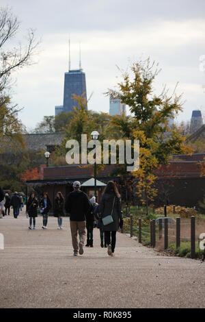 L uomo e la donna giovane a camminare in Lincoln Park Zoo con una vista della Torre di John Hancock. passeggiata nel parco Foto Stock