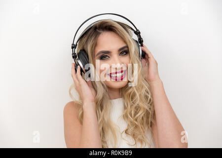 Ritratto di una giovane donna cantante con le cuffie. Ascolto di musica. Canta con un espressione della felicità Foto Stock