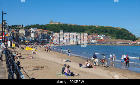 Vista estiva di South Bay beach a Scarborough in North Yorkshire con i turisti per gustare il tradizionale località attività per il tempo libero Foto Stock