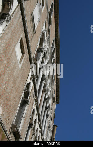 Venezia, un edificio in mattoni con finestre di marmo e colonne, dal di sotto in un cielo blu Foto Stock