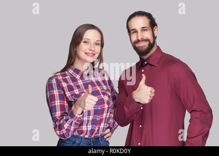 Ritratto di felice soddisfatto uomo barbuto con nero capelli raccolti e la donna in uno stile informale in piedi e guardando la telecamera, sorridente con il pollice in alto. in Foto Stock