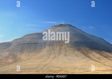 Paesaggio invernale con una collina ricoperta con un giallo erba secca e prima neve sotto il cielo blu scuro in Khakassia Foto Stock