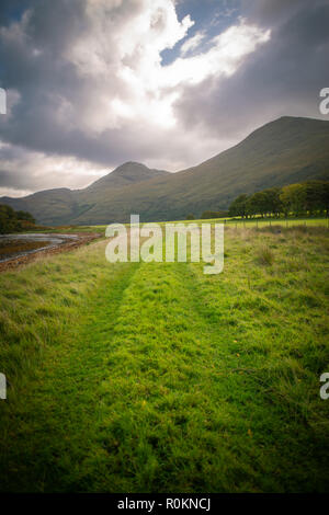 Un percorso accanto a Loch conduce verso le colline nelle Highlands della Scozia Foto Stock