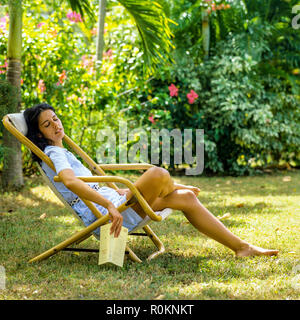 Giovane donna napping in sedia a sdraio, giardino tropicale, Guadalupa, French West Indies, Foto Stock