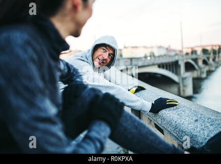 Montare un paio di guide di scorrimento facendo stretching all'aperto sul ponte nella città di Praga. Foto Stock