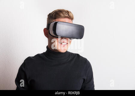 Ritratto di un giovane uomo con la realtà virtuale gli occhiali di protezione in un studio. Foto Stock