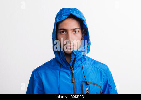 Ritratto di un giovane serio uomo ispanico con blue giacca a vento in un studio. Foto Stock