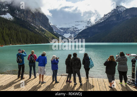 Il Lago Louise, AB, Canada - Giugno 2018: gruppo di turisti in piedi su un pontile in legno sul Lago Louise in Alberta, Canada guardando il paesaggio e tenendo Foto Stock