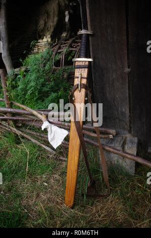 Una spada in un fodero di legno al di fuori di una capanna. Foto Stock