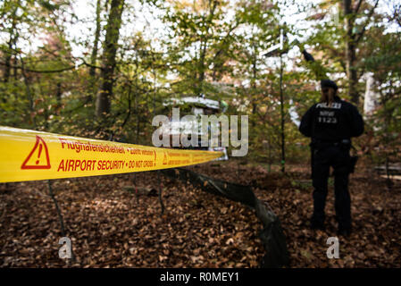 06 novembre 2018, Assia, Mörfelden-Walldorf: c'è un poliziotto in piedi presso l'aeroporto di perimetro di sicurezza. La polizia sgombera il campo della foresta squatter in Trebur Oberwald. Il camp, che è esistito sin dall'inizio dell'anno, protesta contro una possibile eliminazione della foresta. Un raccordo autostradale per il previsto nuovo Terminal a Francoforte/aeroporto principale è quella di essere costruito lì. Foto: Andreas Arnold/dpa Foto Stock