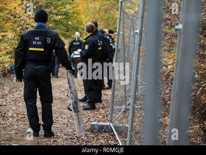 06 novembre 2018, Assia, Mörfelden-Walldorf: un poliziotto supporta su se stesso il suo segno in corrispondenza della barriera recinzione. La polizia sgombera il campo della foresta squatter in Trebur Oberwald. Il camp, che è esistito sin dall'inizio dell'anno, protesta contro una possibile eliminazione della foresta. Un raccordo autostradale per il previsto nuovo Terminal a Francoforte/aeroporto principale è quella di essere costruito lì. Foto: Andreas Arnold/dpa Foto Stock