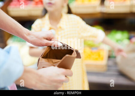 Close-up di un irriconoscibile donna apertura vuota portafoglio marrone e trovare il denaro nel supermercato Foto Stock