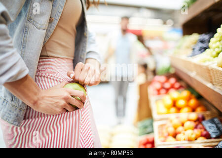 Close-up di un irriconoscibile donna in gonna strippato nascondendo apple in tasca mentre rubare in un negozio di alimentari Foto Stock