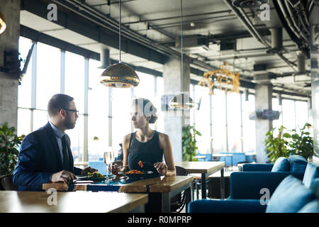 Giovane imprenditore e imprenditrice a pranzo in ristorante di lusso Foto Stock