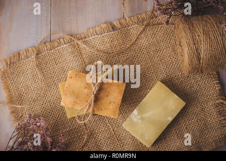 Pezzo di sapone naturale con fiore su un vecchio tavolo in legno Foto Stock