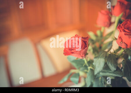 Vaso con le rose rosse in piedi sulla tavola. Celebrare la vita evento, compleanno, il giorno di San Valentino. Romantico casa accogliente dettaglio, uomo acquistare fiori per donna Foto Stock