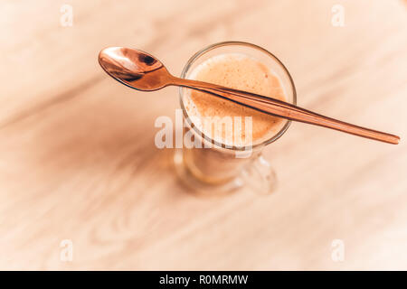 Mattinata rilassante closeup, caffè sul tavolo in legno top in vetro lunghe. Latte per la mattina di motivazione e di inizio giorno Foto Stock