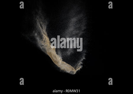 Esplosione di sabbia isolata su sfondo nero. Particelle di astratta cloud. Elemento di tessitura per la progettazione. Foto Stock
