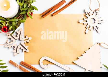 Vista dall'alto su un vuoto foglio d'oro per i saluti tra le decorazioni di Natale su uno sfondo bianco. Piatto, laici mockup. Foto Stock