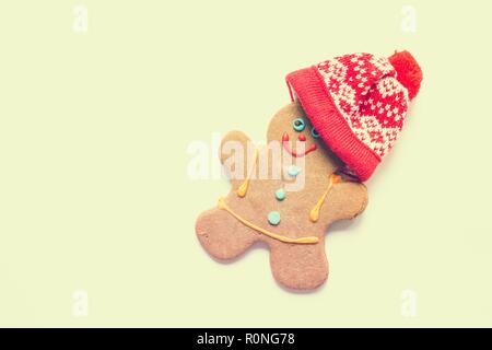 Delizioso pane appena sfornato gingerbread man indossando un cappello a maglia. I cookie si trova su uno sfondo bianco. Deliziosi dolci da forno per il nuovo anno Foto Stock