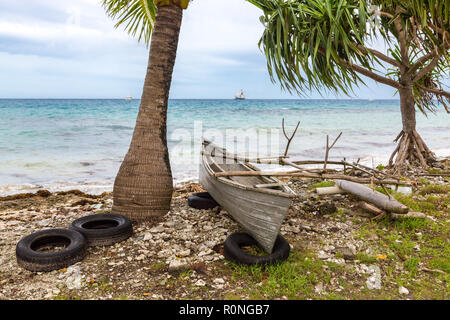 Tradizionale polinesiano canoa outrigger si trova sulla cima di vecchi pneumatici su una spiaggia rocciosa di Funafuti Atoll laguna sotto pandanus. Tuvalu, Polinesia, Oceania Foto Stock