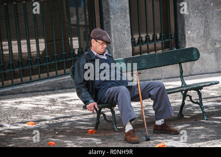 Un vecchio con bastone da passeggio appoggiato su una panchina di strada e addormentarsi Funchal Madeira Foto Stock