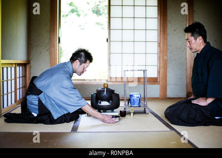 Due uomini giapponesi indossando il tradizionale kimono inginocchiati sul pavimento durante la cerimonia del tè. Foto Stock