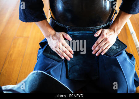 Close up di Kendo fighter inginocchiati sul pavimento e le mani sul giro. Foto Stock