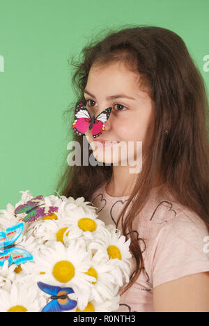 Ritratto di una giovane ragazza con un bouquet di chamomiles. Isolato su sfondo verde. Foto Stock